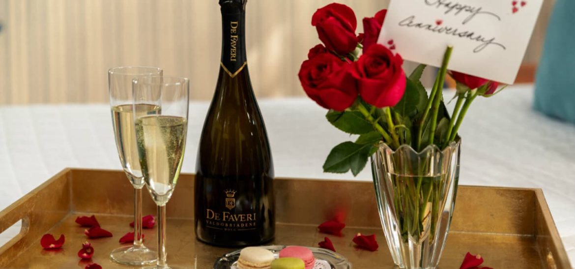 Prosecco, flutes, roses and macaroons on a tray