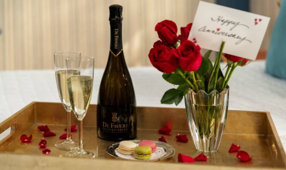 Prosecco, flutes, roses and macaroons on a tray